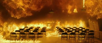 Movie still from “American Dharma” (2018), directed by Errol Morris – A room filled with lots of chairs in front of a fire; Extreme Wide shot, High angle