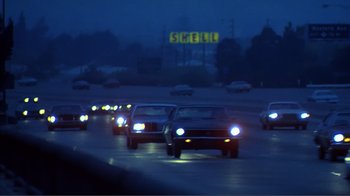 Movie still from “American Gigolo” (1980), directed by Paul Schrader – A group of cars driving down a street at night; Extreme Wide shot, Low angle