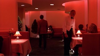 Movie still from “American Gigolo” (1980), directed by Paul Schrader – Two men in suits are standing in a restaurant; Wide shot, Low angle
