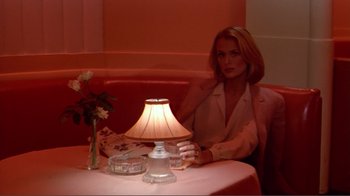 Movie still from “American Gigolo” (1980), directed by Paul Schrader – A woman sitting in front of a lamp on a table; Medium shot, High angle