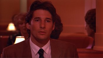 Movie still from “American Gigolo” (1980), directed by Paul Schrader – A man in a suit and tie looking at the camera; Close Up shot, Low angle