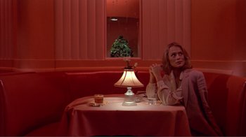 Movie still from “American Gigolo” (1980), directed by Paul Schrader – A woman sitting in front of a table in a restaurant; Medium shot, Low angle