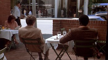 Movie still from “American Gigolo” (1980), directed by Paul Schrader – Two men sitting at a table with wine glasses; Wide shot, Over the shoulder angle