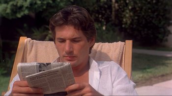 Movie still from “American Gigolo” (1980), directed by Paul Schrader – A man sitting in a lawn chair reading a newspaper; Close Up shot, Over the shoulder angle