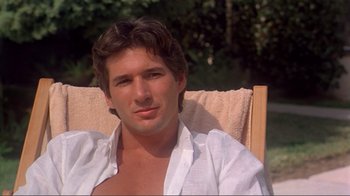 Movie still from “American Gigolo” (1980), directed by Paul Schrader – A person sitting in a lawn chair; Close Up shot, Over the shoulder angle