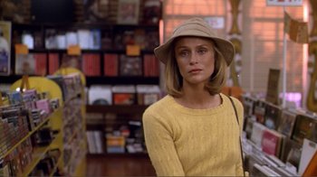 Movie still from “American Gigolo” (1980), directed by Paul Schrader – A woman in a yellow sweater and a tan hat; Medium shot, Over the shoulder angle