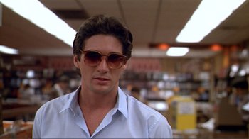 Movie still from “American Gigolo” (1980), directed by Paul Schrader – A person wearing sunglasses in a store; Close Up shot, Low angle