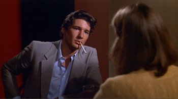 Movie still from “American Gigolo” (1980), directed by Paul Schrader – A man sitting in front of a woman in front of a mirror; Close Up shot, Over the shoulder angle
