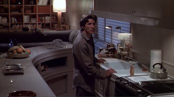 Movie still from “American Gigolo” (1980), directed by Paul Schrader – A man standing in a kitchen next to a sink; Medium shot, High angle