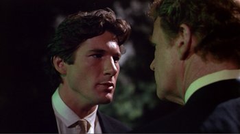 Movie still from “American Gigolo” (1980), directed by Paul Schrader – A man in a suit and tie talking to another man in a suit and tie; Close Up shot, Over the shoulder angle