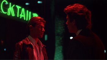 Movie still from “American Gigolo” (1980), directed by Paul Schrader – Two young men are talking in a dark room; Close Up shot, Over the shoulder angle