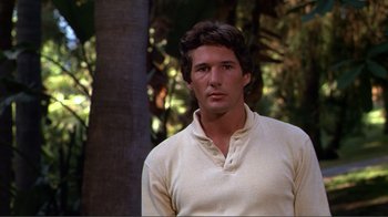 Movie still from “American Gigolo” (1980), directed by Paul Schrader – A man in a white shirt is standing in the woods; Close Up shot, Over the shoulder angle
