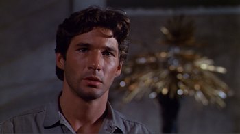 Movie still from “American Gigolo” (1980), directed by Paul Schrader – A person wearing a gray shirt; Close Up shot, Over the shoulder angle