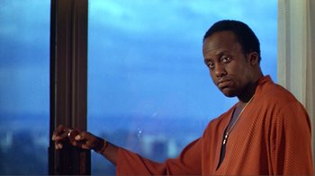 Movie still from “American Gigolo” (1980), directed by Paul Schrader – A man in an orange robe is holding a remote control; Close Up shot, Low angle