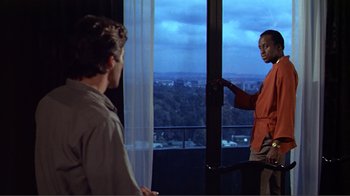 Movie still from “American Gigolo” (1980), directed by Paul Schrader – Two men standing in front of a window looking at each other; Medium shot, Over the shoulder angle