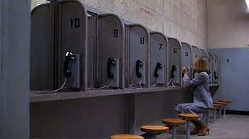 Movie still from “American Gigolo” (1980), directed by Paul Schrader – A man sitting on a bench next to a row of phone booths; Wide shot, High angle