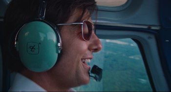 Movie still from “American Made” (2017), directed by Doug Liman – A man in a helicopter smiling at the camera; Close Up shot, Overhead angle