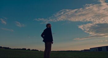Movie still from “American Made” (2017), directed by Doug Liman – A man standing in a field looking up at the sky; Extreme Wide shot, Low angle