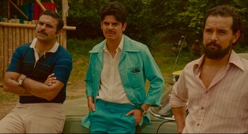 Movie still from “American Made” (2017), directed by Doug Liman – A man in a blue suit standing next to a boat; Medium shot, Low angle