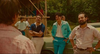 Movie still from “American Made” (2017), directed by Doug Liman – A group of men standing next to each other near trees; Medium shot, Over the shoulder angle