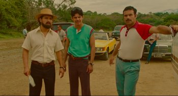 Movie still from “American Made” (2017), directed by Doug Liman – A group of men standing next to each other on a dirt road; Medium shot, Low angle
