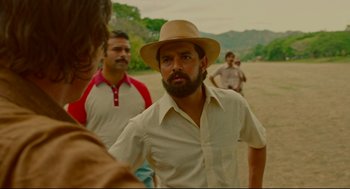Movie still from “American Made” (2017), directed by Doug Liman – A group of men standing on top of a dirt field; Medium shot, Over the shoulder angle