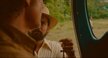 Movie still from “American Made” (2017), directed by Doug Liman – A man with a beard and a hat is holding a cigarette; Close Up shot, Over the shoulder angle