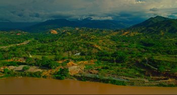 Movie still from “American Made” (2017), directed by Doug Liman – An airplane is flying low over a river and mountains; Extreme Wide shot, High angle