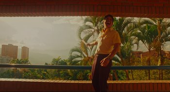 Movie still from “American Made” (2017), directed by Doug Liman – A man standing in front of a window with trees in the background; Medium shot, Low angle