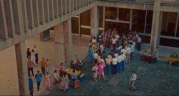 Movie still from “American Made” (2017), directed by Doug Liman – A group of people standing outside of a building; Extreme Wide shot, Overhead angle