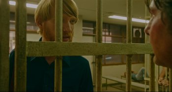 Movie still from “American Made” (2017), directed by Doug Liman – A man standing behind bars in a jail cell; Close Up shot, Over the shoulder angle