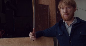 Movie still from “American Made” (2017), directed by Doug Liman – A man with a red beard holding onto a wooden stick; Medium shot, Low angle
