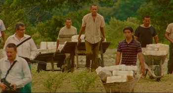 Movie still from “American Made” (2017), directed by Doug Liman – A group of men standing next to each other near a pile of boxes; Wide shot, Low angle