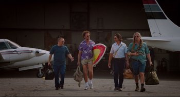 Movie still from “American Made” (2017), directed by Doug Liman – A group of people walking on the ground with surfboards; Wide shot, Low angle