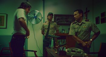 Movie still from “American Made” (2017), directed by Doug Liman – A group of men standing around a table; Medium shot, Low angle