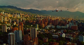 Movie still from “American Made” (2017), directed by Doug Liman – An airplane flying over a large city with tall skyscrapers; Extreme Wide shot, High angle