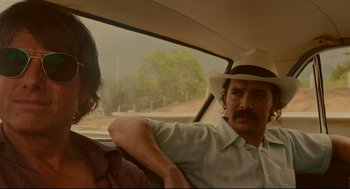Movie still from “American Made” (2017), directed by Doug Liman – A man in a hat and a woman in a hat in the back of a car; Close Up shot, Low angle
