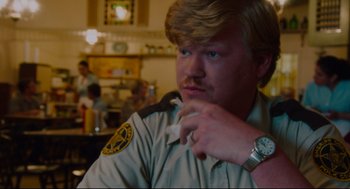 Movie still from “American Made” (2017), directed by Doug Liman – A man in a police uniform sitting at a table; Close Up shot, Over the shoulder angle