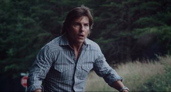 Movie still from “American Made” (2017), directed by Doug Liman – A man in a striped shirt is standing in the grass; Close Up shot, Over the shoulder angle
