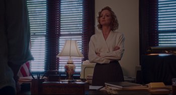 Movie still from “American Made” (2017), directed by Doug Liman – A woman standing in front of a lamp in a room; Medium shot, Low angle
