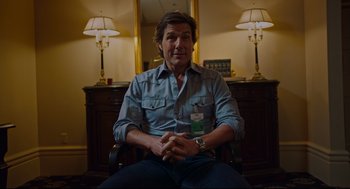 Movie still from “American Made” (2017), directed by Doug Liman – A man sitting in front of a desk in a room; Medium shot, Over the shoulder angle