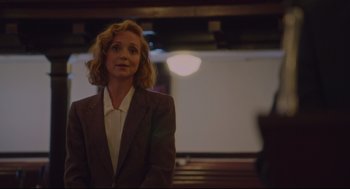 Movie still from “American Made” (2017), directed by Doug Liman – A woman standing in a room with her hands in her pockets; Medium shot, Over the shoulder angle