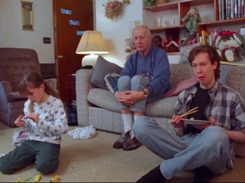 A group of people sitting in a living room playing wii