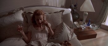 Movie still from “American Psycho” (2000), directed by Mary Harron – A woman laying on a couch talking on a phone; Medium shot, High angle