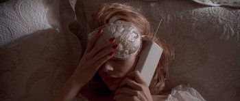 Movie still from “American Psycho” (2000), directed by Mary Harron – A woman with a blindfold is holding a cell phone; Close Up shot, Overhead angle