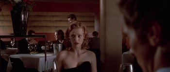 Movie still from “American Psycho” (2000), directed by Mary Harron – A woman in a strapless black dress sitting at a table; Close Up shot, Over the shoulder angle