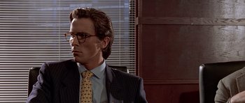 Movie still from “American Psycho” (2000), directed by Mary Harron – A man in a suit and tie sitting in front of a window; Close Up shot, Over the shoulder angle