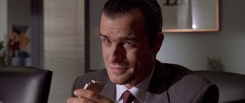 Movie still from “American Psycho” (2000), directed by Mary Harron – A person wearing a suit holding a cigarette; Close Up shot, Low angle