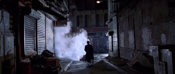 Movie still from “American Psycho” (2000), directed by Mary Harron – A man walking down the street with a bag of luggage; Wide shot, Low angle
