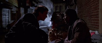Movie still from “American Psycho” (2000), directed by Mary Harron – Two people and a dog in a dark alley; Medium shot, Over the shoulder angle